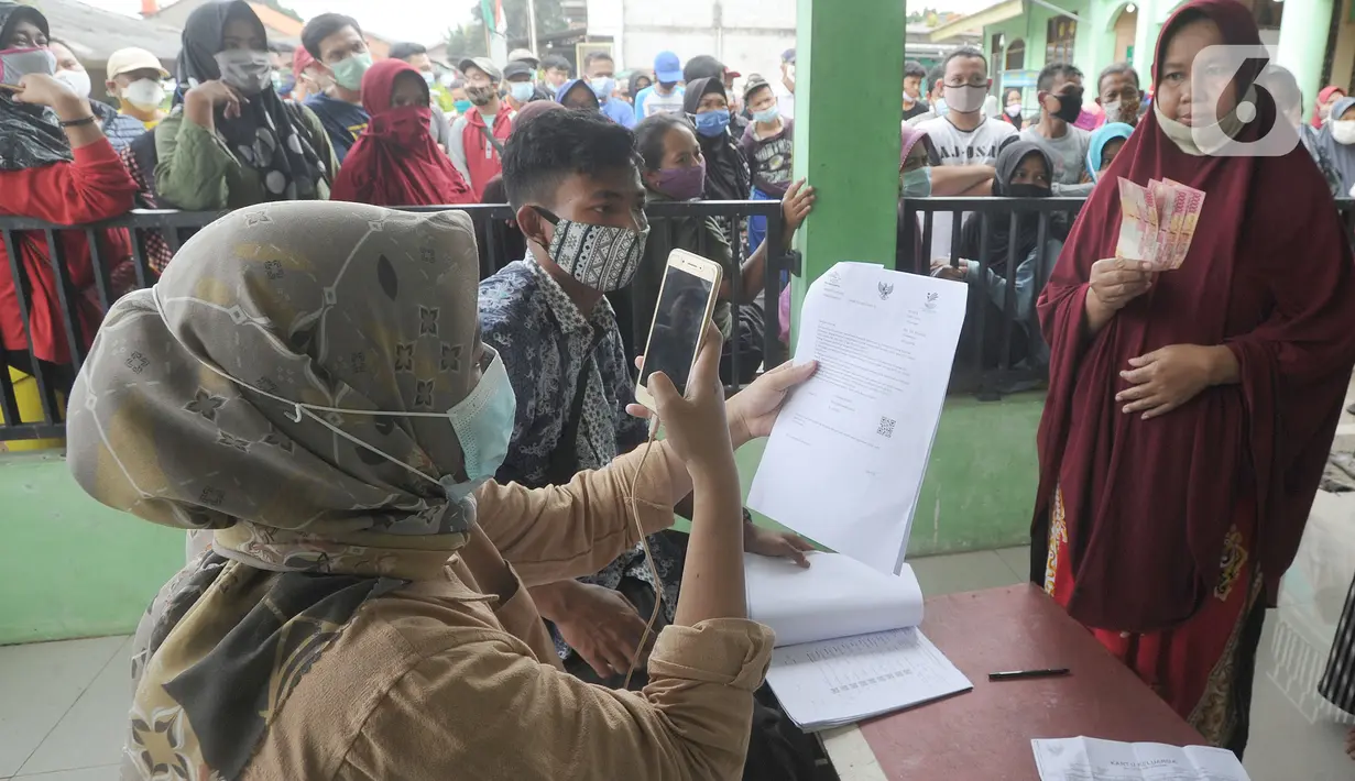 Petugas PT Pos Indonesia memotret wajah penerima Bantuan Sosial Tunai (BST) bulan Januari di halaman Masjid Jami Al-Hidayah RW 01 Bedahan, Depok, Selasa (16/2/2021). Sekitar 159.470 Keluarga Penerima Manfaat (KPM) di Kota Depok menerima BST yang disalurkan pada Februari ini (merdeka.com/Arie Basuki)