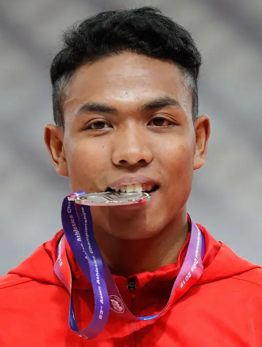 Sprinter Indonesia, Lalu Muhammad Zohri menggigit medali usai mengikuti kategori 100 meter dalam Kejuaraan Atletik Asia di Doha, Qatar, Senin (22/4). Zohri merebut medali perak dengan catatan waktu 10,13 detik yang juga memecahkan rekor pelari tercepat Asia Tenggara, Suryo Agung. (AP/Vincent Thian)