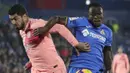 Striker Barcelona, Luis Suarez, berebut bola dengan pemain Getafe, Djene, pada laga La Liga di Stadion Alfonso Perez, Minggu (6/1). Barcelona menang 2-1 atas Getafe. (AP/Manu Fernandez)