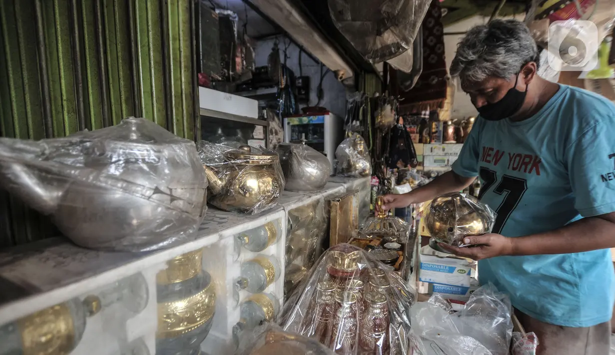 Budi (54) merapikan barang yang dijual di toko oleh-oleh haji di Jalan Raya Pondok Gede, Jakarta, Rabu (21/7/2021). Larangan ibadah haji dan umrah akibat pandemi di Indonesia menyebabkan penjualan oleh-oleh khas Makkah di depan Asrama Haji Pondok Gede merosot tajam. (merdeka.com/Iqbal S. Nugroho)