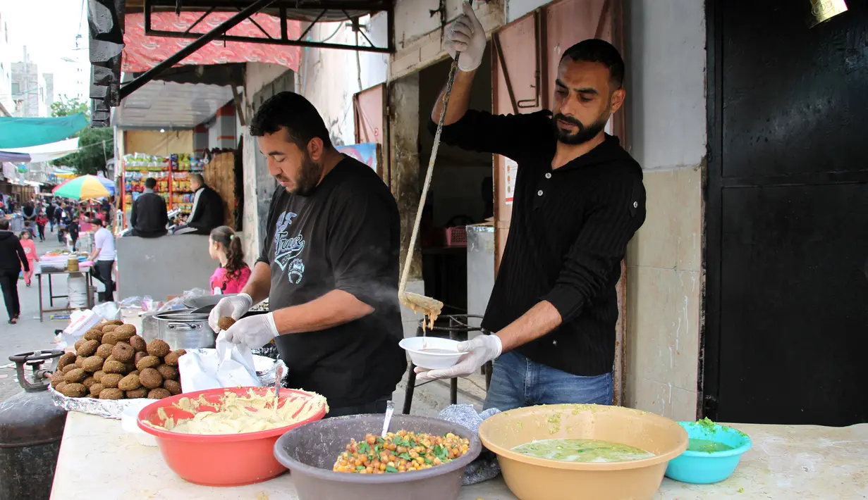 Seorang pekerja Palestina membagikan makanan gratis pada hari keempat Ramadan di Deir al-Balah, Jalur Gaza tengah, pada 27 April 2020. Warga Palestina merayakan Ramadan, bulan suci umat Islam, di tengah situasi ekonomi yang memburuk akibat pandemi COVID-19. (Xinhua/Rizek Abdeljawad)
