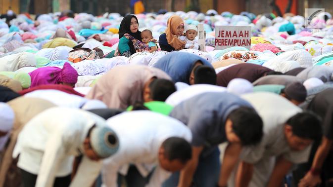 Dua orang ibu menggendong anak mereka saat umat muslim melaksanakan salat Idul Adha 1439 H di Monumen Perjuangan Jatinegara, Jakarta Timur, Rabu (22/8). (Liputan6.com/JohanTallo)