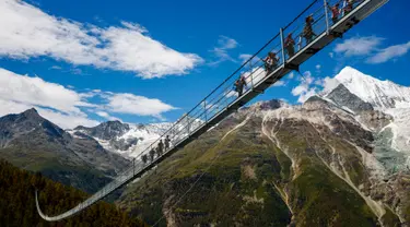 Wisatawan berjalan di atas jembatan gantung yang baru saja diresmikan di Kota Zermatt, Swiss, 29 Juli 2017. Jembatan sepanjang hampir 500 meter ini disebut-sebut sebagai jembatan gantung pejalan kaki terpanjang di dunia (Valentin Flauraud/Keystone via AP)