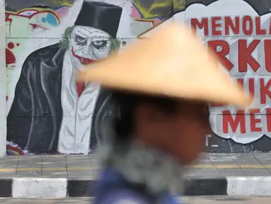 Mural bertulis 'Menolak RKUHP Bukan Menunda' terpampang pada dinding di Jalan Pemuda, Rawamangun, Jakarta, Selasa (1/10/2019). Mural tersebut respons dari seniman Jakarta terhadap RUU KUHP yang dinilai mencederai tatanan demokrasi. (merdeka.com/Iqbal Nugroho)