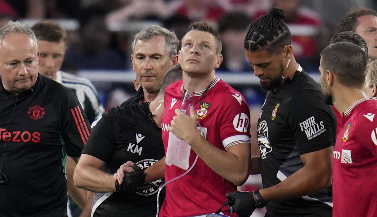 Pemain Wrexham, Paul Mullin dengan menggunakan alat bantu pernapasan dibantu sejumlah tim medis meninggalkan lapangan pertandingan setelah mengalami insiden dengan kiper Manchester United, Nathan Bishop pada laga uji coba pramusim di Snapdragon Stadium, San Diego, California, Rabu (25/07/2023) WIB. (AP Photo/Gregory Bull)