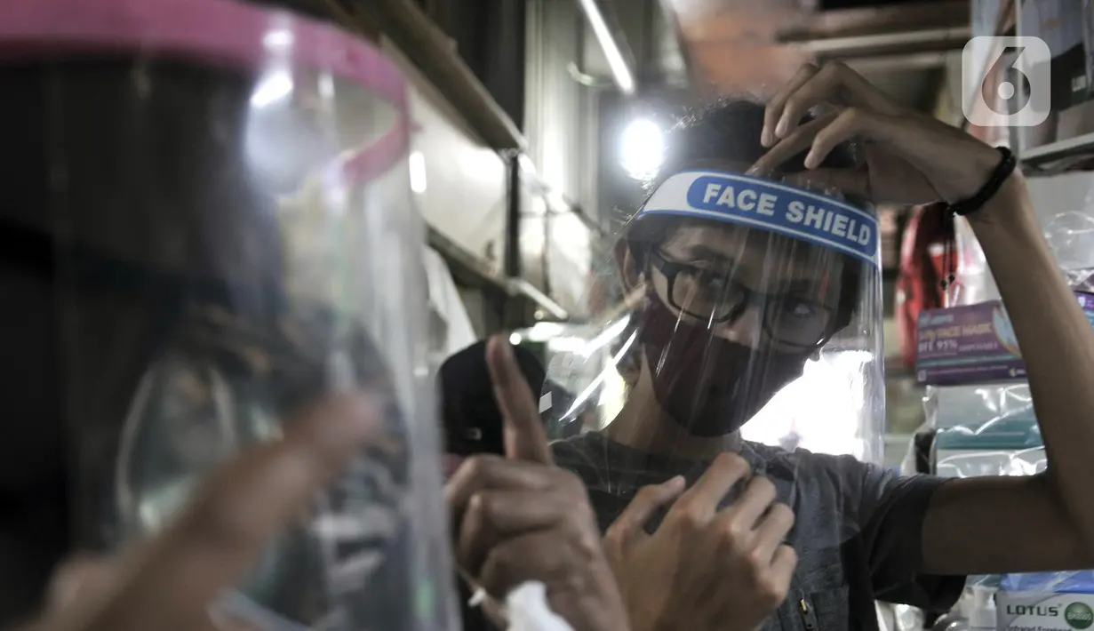 Pembeli mencoba alat pelindung wajah atau face shield di salah satu kios Pasar Pramuka, Jakarta, Rabu (3/6/2020). Pemerintah mewajibkan petugas pelayanan, pedagang, serta pekerja toko swalayan dan mal mengenakan face shield saat fase new normal diterapkan. (merdeka.com/Iqbal S. Nugroho)
