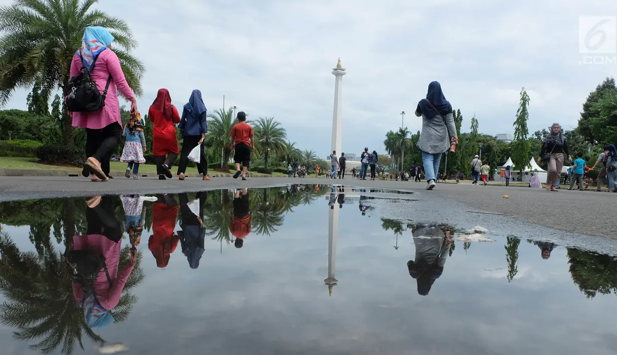 Sejumlah pengunjung berjalan saat sedang liburan di Monumen Nasional (monas), Jakarta, Selasa (25/12). Liburan Natal 2018, banyak warga datang bersama kerabat maupun keluarga memadati Monas. (Liputan6.com/Herman Zakharia)