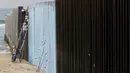 Sejumlah orang mengecat pagar perbatasan antara Meksiko dan Amerika Serikat di Playas Tijuana, Meksiko (10/12). Tembok dan pagar pembatas ini dibuat untuk mencegah masuknya imigran gelap Meksiko ke Amerika Serikat. (Reuters/Jorge Duenes)