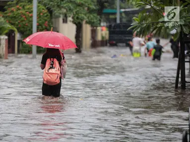 Seorang warga melintasi banjir di jalan Pd. Karya, Jakarta, Kamis (13/12). Hujan yang mengguyur Jakarta Sore tadi menyebabkan banjir setinggi 40cm  menggenangi kawasan Jalan Pd. Karya dan Jalan Bangka. (Liputan6.com/Faizal Fanani)