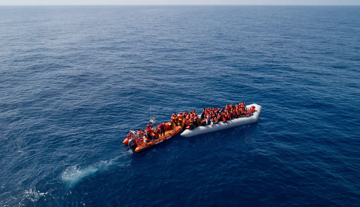 Momen saat LSM Proactiva Open Arms Spanyol menyelamatkan pengungsi dan imigran di utara pantai Libya, Minggu (6/5). Para pengungsi dan imigran menaiki perahu karet yang penuh sesak. (AP Photo/Felipe Dana)