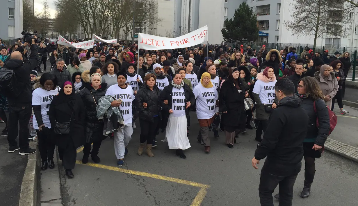 Pengunjuk rasa membawa poster bertuliskan 'Keadilan untuk Theo' saat berdemo di jalanan Aulnay-sous-Bois, utara Paris, Prancis, Senin (6/2). Mereka mengecam tindakan seorang polisi yang menyodomi pemuda berusia 22 tahun, Theo. (AP Photo/Milos Krivokapic)