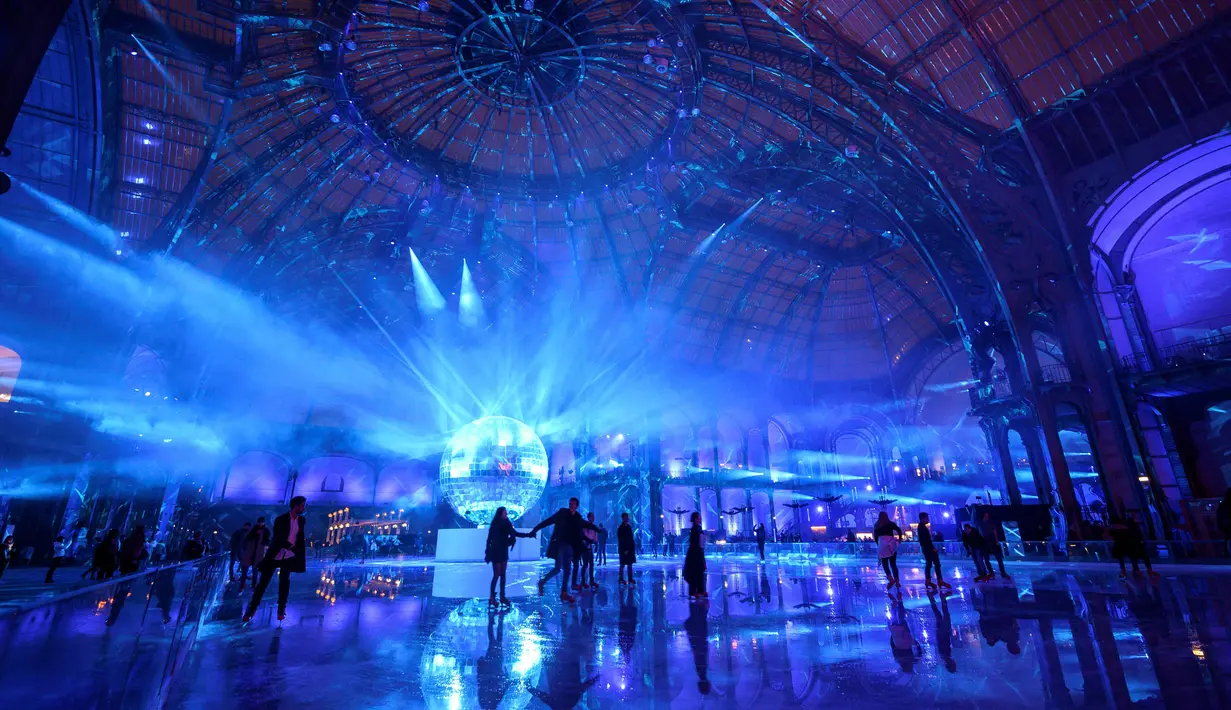Orang-orang berseluncur di arena ice skating di bawah kubah kaca mewah legendaris, Grand Palais, Paris, Selasa (17/12/2019). Aren seluncur es musiman ini terbuka untuk umum selama liburan Natal. (Photo by Thomas SAMSON / AFP)