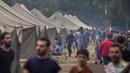 Para migran berjalan di dalam kamp pengungsi yang baru dibangun di tempat latihan militer Rudninkai, sekitar 38km (23,6 mil) selatan dari Vilnius, Lituania, Rabu (4/8/2021). (AP Photo/Mindaugas Kulbis)