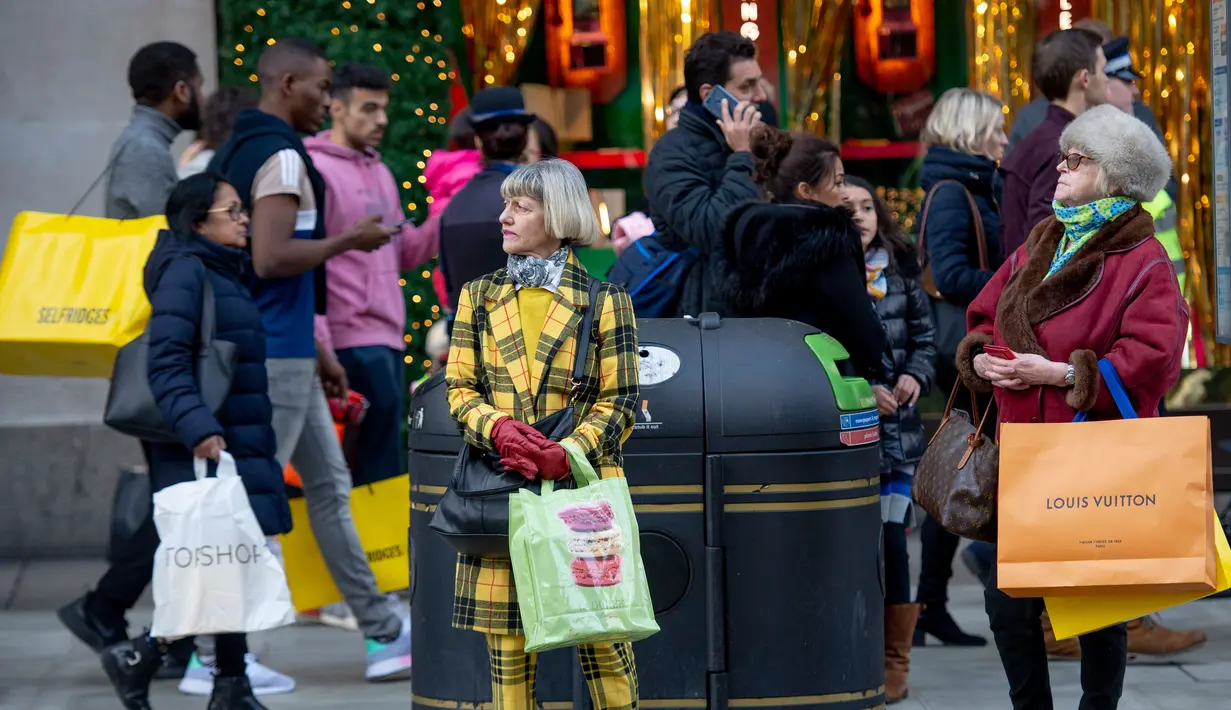 Pembeli berdiri sambil membawa kantong belanjaan di Oxford Street, London pada Sabtu (22/12). Setiap hari Oxford Street yang merupakan salah satu pusat perbelanjaan selalu ramai, namun menjelang natal keramaiannya meningkat. (NIKLAS HALLE'N/AFP)