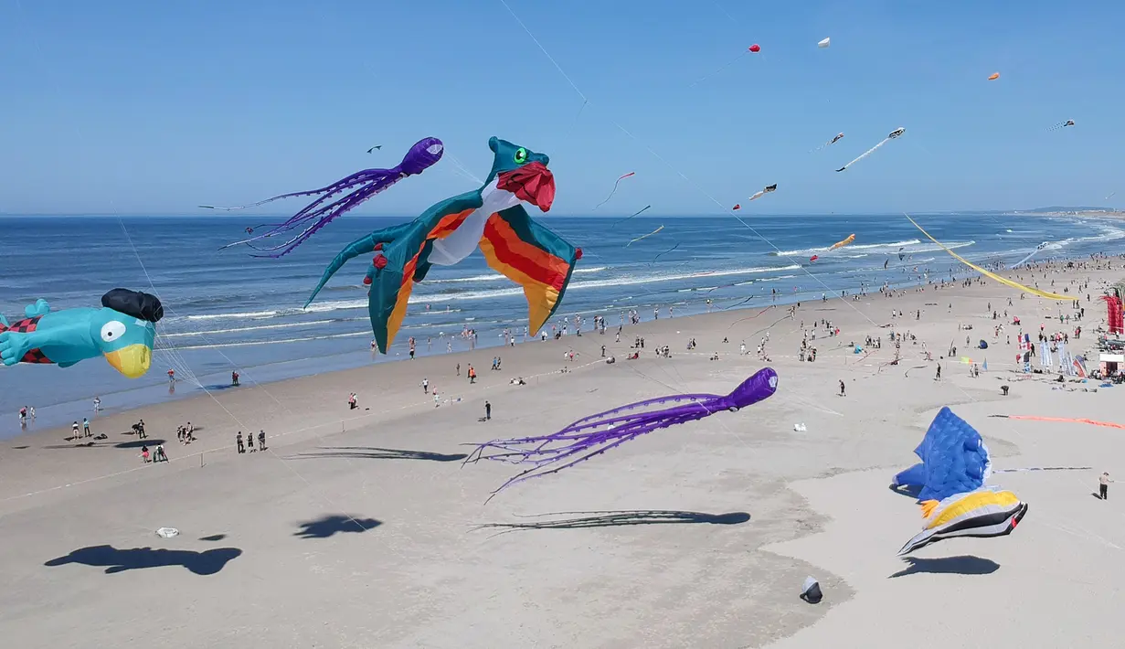 Sejumlah layang-layang berbagai bentuk dan warna memeriahkan Festival Layang-Layang Internasional ke-32 di pantai Berck-sur-Mer, Prancis utara, 18 April 2018. Uniknya, layang-layang terbuat dari kain parasut yang diikat puluhan tali. (Denis Charlet/AFP)
