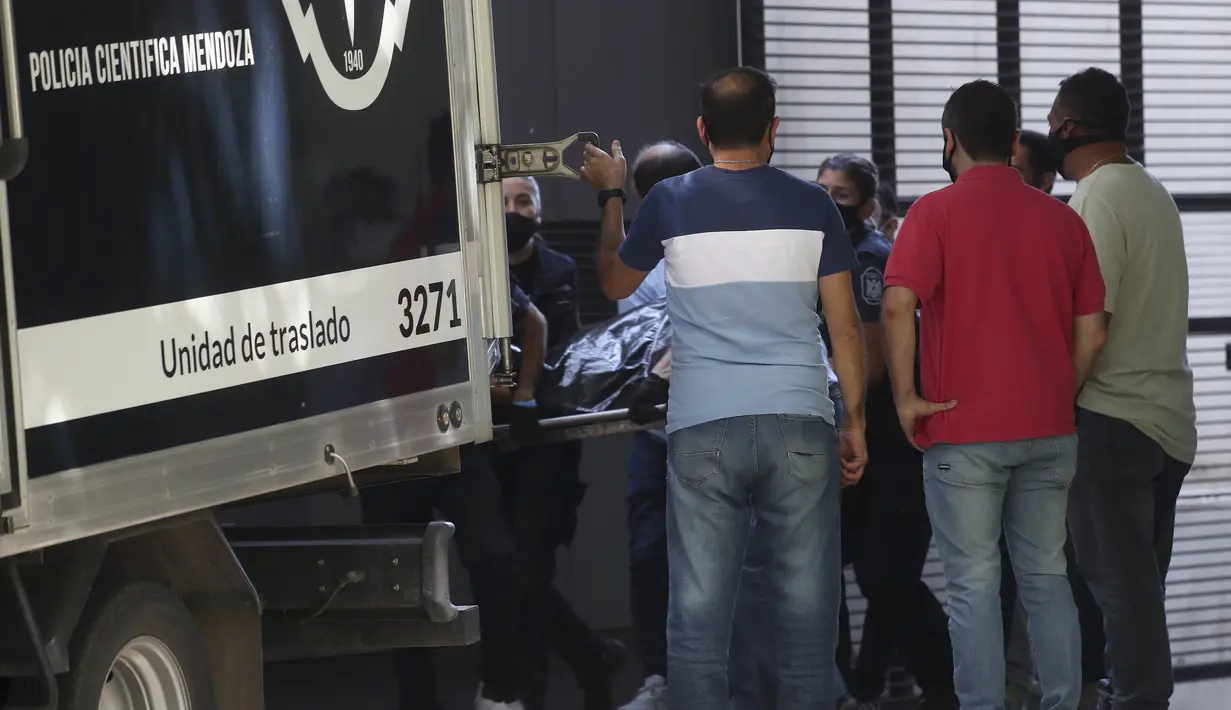 Jenazah penyerang klub Argentina Godoy Cruz, Santiago ‘Morro’ Garcia dikeluarkan dari apartemennya dan dimasukkan ke dalam mobil forensik, di Mendoza, Argentina, Sabtu (6/2/2021). Garcia yang diketahui sedang dalam masa terapi karena depresi ditemukan tewas diduga bunuh diri. (AP Photo/Marcelo Ruiz)