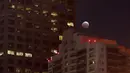 Bulan yang sedang memerah dipadukan dengan lansekap gedung-gedung tinggi terlihat di Los Angeles, California, Sabtu (4/4/2015). (David McNew/Getty Images/AFP)