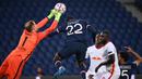 Kiper RB Leipzig, Peter Gulacsi (kiri) meninju bola dari ancaman bek Paris Saint Germain, Abou Diallo, dalam laga lanjutan Liga Champions 2020/21 di Parc des Princes Stadium, Paris, Rabu (25/11/2020). Leipzig kalah 0-1 dari PSG. (AFP/Franck Fife)