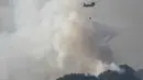 Sebuah helikopter Pasukan Bela Diri Jepang menjatuhkan air ke bagian depan kobaran api di dekat kota Otsuchi, Prefektur Iwate, Jepang pada Sabtu 25 April 2026. Hingga Ribuan petugas pemadam kebakaran masih berjuang memadamkan kebakaran hutan wilayah Otsuchi, Prefektur Iwate, Jepang. (ANDREW CABALLERO-REYNOLDS/AFP)
