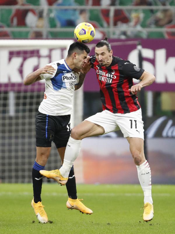 Penyerang AC Milan, Zlatan Ibrahimovic berebut bola udara dengan bek Atalanta, Cristian Romero pada pertandingan lanjutan Liga Serie A Italia di Stadion San Siro, Minggu (24/1/2021). AC Milan tumbang atas Atalanta dengan skor telak 0-3. (AP Photo/Antonio Calanni)