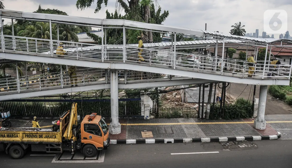 Petugas Sudin Bina Marga Jakarta Timur memperbaiki jembatan penyeberangan orang (JPO) di Jalan Otto Iskandardinata (Otista), Jatinegara, Rabu (9/2/2022). Perbaikan JPO itu tindak lanjut pasca insiden tertimpa pohon tumbang pada November tahun lalu akibat cuaca ekstrem. (merdeka.com/Iqbal S Nugroho)