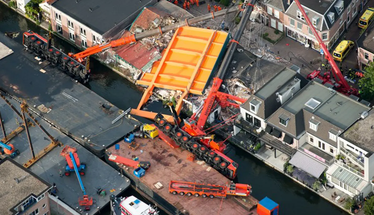 Sebuah gambar menunjukkan mesin derek yang jatuh ke rumah warga di Alphen aan den Rijn, Belanda, Senin (3/8/2015). Dua mesin derek yang sedang memperbaiki jembatan ambruk ke rumah yang ada di dekatnya dan melukai 20 orang. (AFP PHOTO/ANP/LEX VAN LIESHOUT)