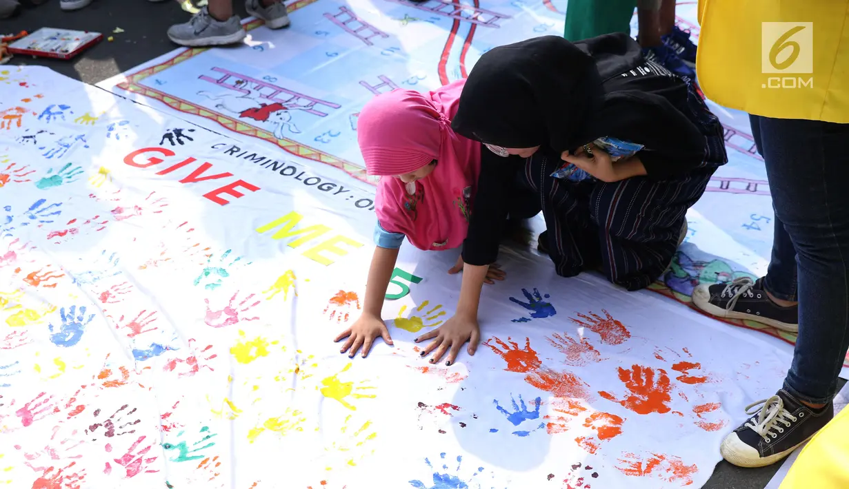 Mahasiswa jurusan Kriminologi Fisip UI mendampingi anak-anak bermain cap tangan saat gelaran Car Free Day di kawasan Bundaran HI, Jakarta, Minggu (18/11). Permainan ini bertujuan mengurangi anak-anak bermain gawai. (Liputan6.com/Helmi Fithriansyah)