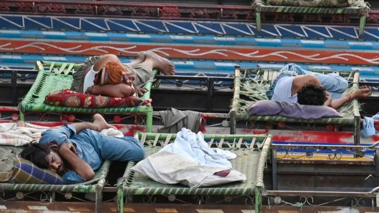 Para sopir bus juga memanfaatkan atap bus untuk tidur nyenyak di bawah pohon rindang. Foto: ARIF ALI / AFP<br>