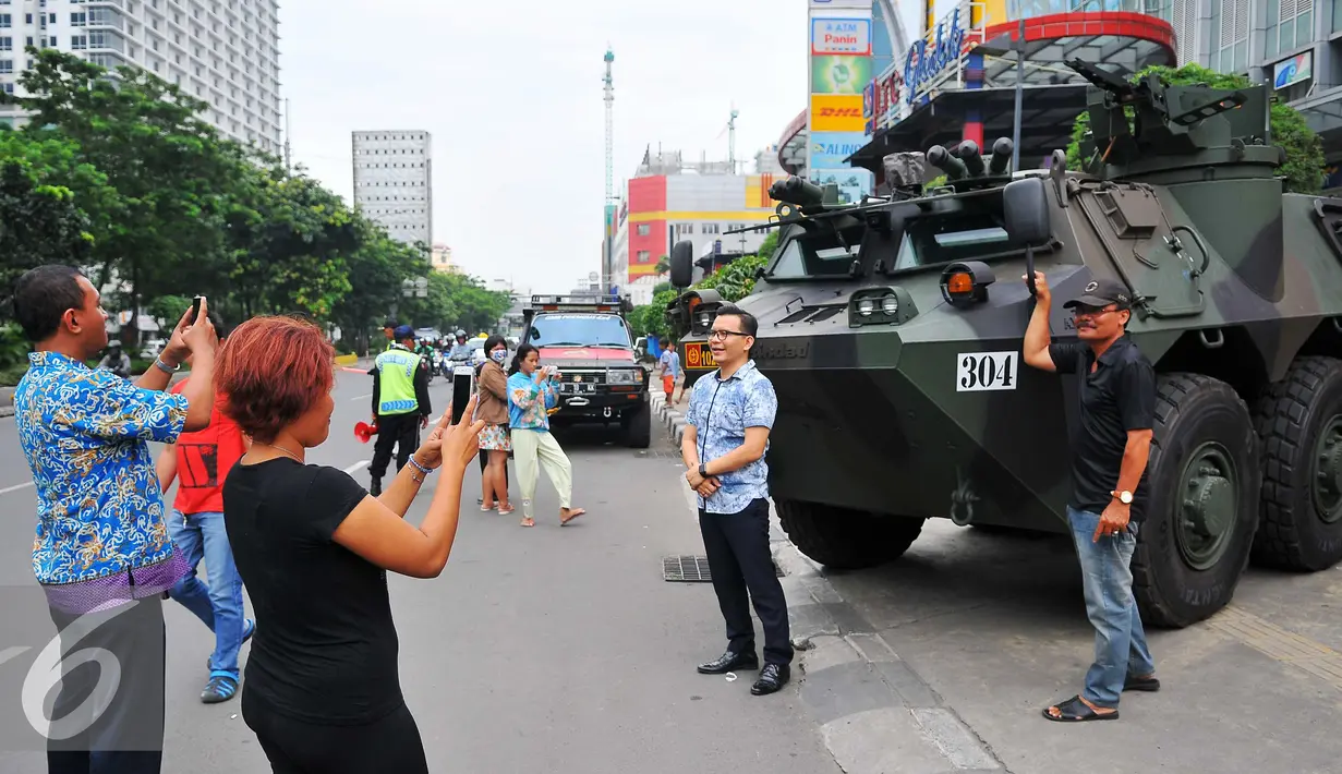 Sejumlah warga  melakukan selfie dengan latar belakang panser Anoa milik TNI di LTC Glodok, Jakarta, Jumat (4/11). Pengamanan ini merupakan bentuk kerja sama antara TNI-Polri dalam menjaga keamanan terkait demo bela islam . (Liputan6.com/Angga Yuniar)
