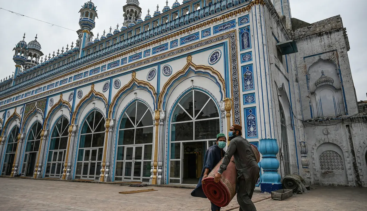 Umat Muslim melepas karpet sajadah dari aula utama masjid menyusul pembatasan baru pemerintah baru menjelang Ramadan di Rawalpindi, Pakistan, Senin (5/4/2021). Sesuai pedoman, warga juga diminta menghindari sholat di jalan atau trotoar dan melarang warga untuk berwudhu di masjid. (Aamir QURESHI/AFP)