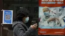 Seorang wanita mengenakan masker berjalan di dekat poster yang mempromosikan vaksinasi COVID-19 di pusat kesehatan masyarakat di Beijing, Rabu (26/10/2022). Kota Shanghai di China mulai memberikan vaksin COVID-19 yang dapat dihirup pada hari Rabu di tempat yang tampaknya menjadi yang pertama di dunia. (AP/Andy Wong)
