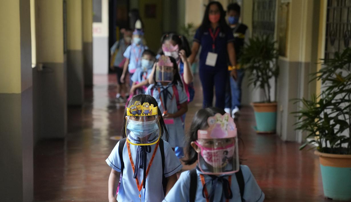 Siswa TK dengan masker dan pelindung wajah berjalan pada hari pertama kelas tatap muka di sekolah dasar Comembo di kota Makati, Filipina, Senin (6/12/2021). Beberapa sekolah di Manila diizinkan dibuka kembali setelah berbulan-bulan lamanya karena kasus COVID-19 terus menurun. (AP Photo/Aaron Favila)