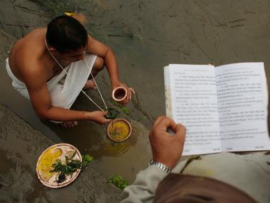 Umat Hindu Nepal melakukan ritual pemujaan dengan bantuan pemuka agama saat festival Kuse Aunsi di kuil Hindu Gokarneshwar di Kathmandu, Nepal (21/8). Kushe Aunsi merupakan bentuk perayaan Hari Ayah bagi masyarakat Nepal. (Niranjan Shrestha/AP) 