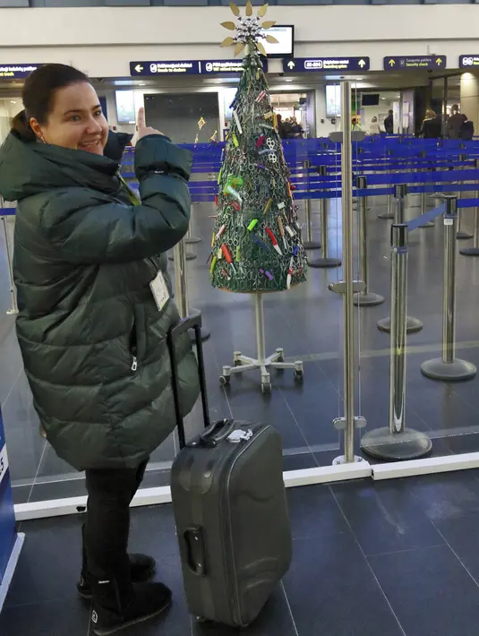 Seorang perempuan mengambil gambar Pohon Natal dari barang-barang sitaan di Bandara Vilnius, Lithuania pada 12 Desember 2019. Bandara Lithuania mengatakan pohon ini dikumpulkan dari barang-barang terlarang yang disita petugas selama proses penyaringan. (Photo by Petras Malukas / AFP)