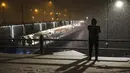 Seorang pria berdiri di samping jembatan Galata saat hujan salju di Istanbul, Turki, Sabtu (12/3/2022). Salju tebal menutupi Istanbul dan mengganggu lalu lintas udara menyebabkan transportasi laut serta darat terhenti, hingga memaksa penutupan sekolah. (AP Photo/Emrah Gurel)