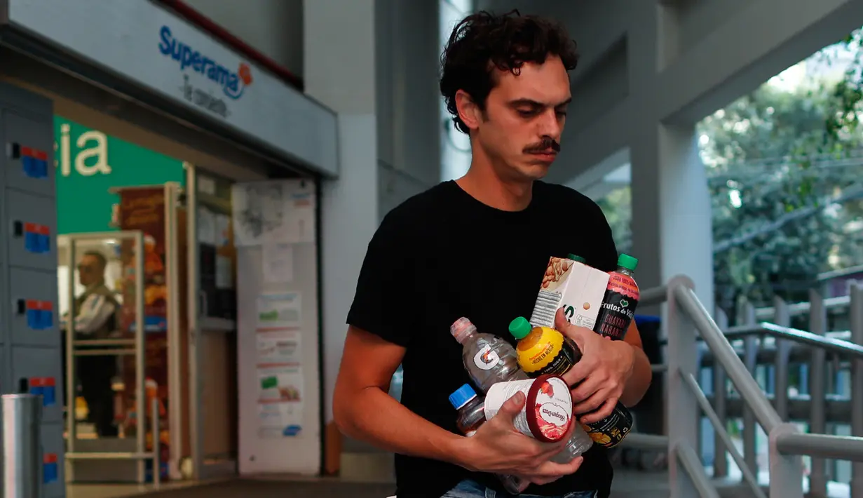 Seorang pria membawa barang-barangnya di pelukannya saat meninggalkan toko grosir di Mexico City pada 1 Januari 2020. Toko-toko berhenti menyediakan kantong plastik sekali pakai kepada pelanggan sesuai undang-undang yang berlaku di ibu kota Meksiko. (AP/Rebecca Blackwell)
