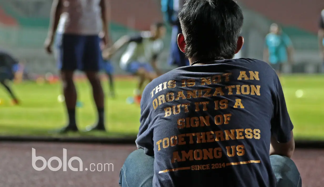 Seorang pekerja tengah serius menyaksikan para pemain Arema FC berlatih di Stadion Pakansari, Bogor, Jumat (10/3/2017). Arema FC akan melawan Pusamania Borneo FC pada laga Final Piala Presiden 2017. (Bola.com/Nicklas Hanoatubun)