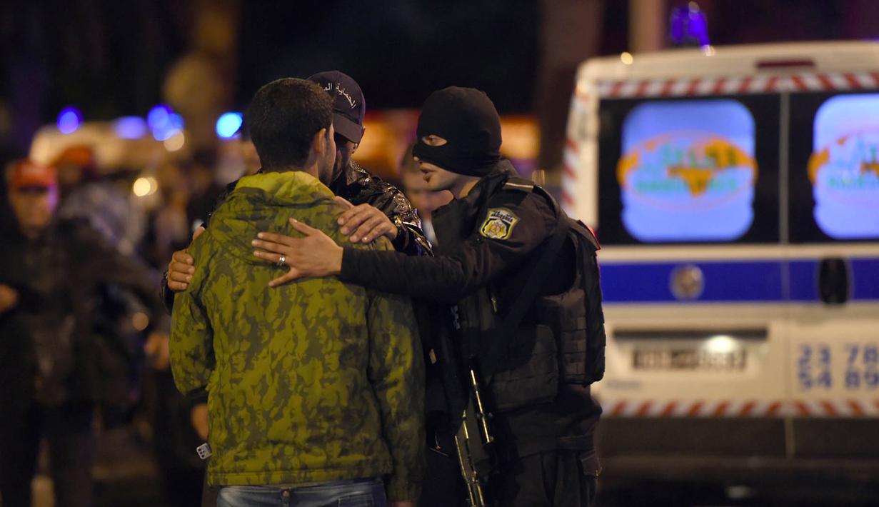 Petugas memenangkan keluarga korban usai ledakan sebuah bus yang mengangkut pengawal Presiden Tunisia di Tunis, Selasa (24/11). Insiden yang diduga akibat serangan bom bunuh diri itu menewaskan 12 orang dan melukai 16 lainnya. (AFP PHOTO/Fethi Belaid)