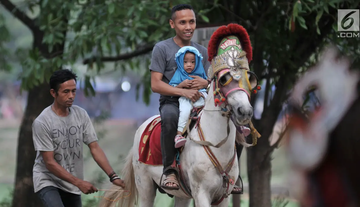 Seorang pria bersama anaknya menunggangi kuda saat menunggu waktu berbuka puasa atau ngabuburit di kawasan Kanal Banjir Timur, Jakarta, Selasa (5/6). Warga cukup mengeluarkan uang sebesar Rp 10 ribu untuk menaiki kuda. (Merdeka.com/Iqbal S. Nugroho)