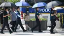 Petugas polisi menggunakan payung untuk melindungi diri dari terik matahari di sebuah jalan di Seoul,  Korea Selatan, Senin,  3 Agustus 2026. (AFP/  Jung Yeon-je)