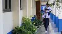 Siswa berjalan di lorong saat akan mengikuti hari pertama pembelajaran tatap muka di SMP 26 Depok, Depok, Jawa Barat, Senin (24/1/2022). Pemerintah Kota Depok mulai menggelar Pembelajaran Tatap Muka (PTM) secara penuh atau 100 persen mulai hari ini. (Liputan6.com/Herman Zakharia)