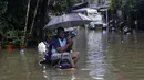 Seorang pria duduk duduk memegang payung di atas sepeda motor yang diparkir di jalan yang tergenang air setelah hujan lebat di Mumbai, India, Rabu (23/9/2020). Musim hujan di India berlangsung dari Juni hingga September. (AP Photo/Rajanish Kakade)