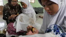 Pengajar dari Komunitas Batik Cibuluh memberikan pelatihan membatik kepada muird SLB Mekar Sari 1 Cibinong, Bogor, Jawa Barat, Rabu (18/9/2019). Ekstrakurikuler yang rutin dilaksanakan seminggu sekali ini untuk membekali para siswa keterampilan membatik. (merdeka.com/Arie Basuki)
