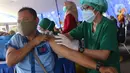 Vaksinator menyuntikkan vaksin COVID-19 kepada sopir transportasi umum di Terminal Poris Plawad, Cipondoh, Kota Tangerang, Kamis (4/3/2021). Ada sebanyak 1.000 peserta pekerja transportasi mulai dari sopir angkot, bus, taksi dan ojek yang divaksinasi Covid-19. (Liputan6.com/Angga Yuniar)