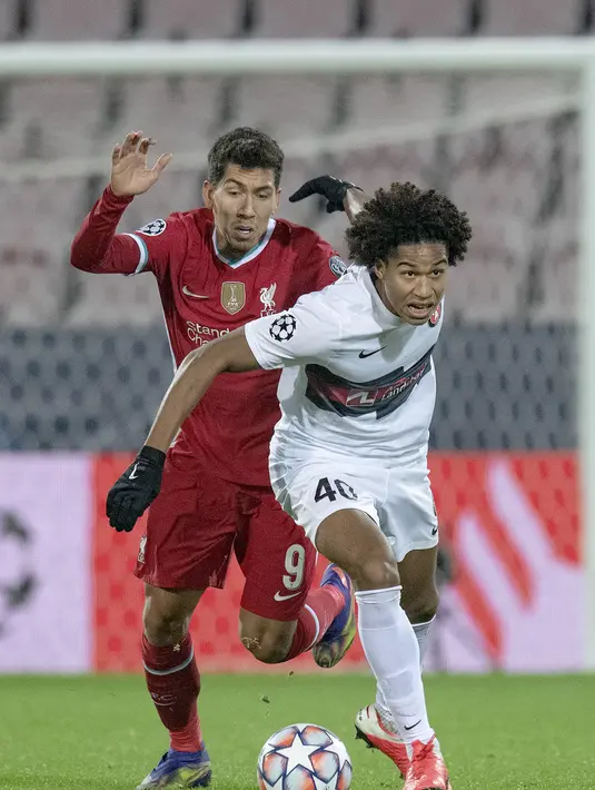 Penyerang Liverpool, Firmino berusaha merebut bola dari pemain Midtjylland, Jens-Lys Cajuste pada pertandingan Grup D Liga Champions di MCH Arena di Herning, Denmark, Kamis (10/12/2020). Liverpool bermain imbang atas Midtjylland 1-1. (Bo Amstrup/Scanpix via AP)
