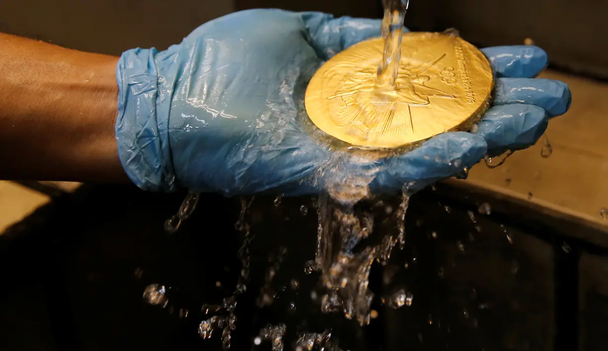 Pekerja mencuci medali setelah selesai proses pengecatan di Casa da Moeda do Brasil (Brazilian Mint), Rio de Janeiro, Brasil, (28/6). Berat medali ini hanya sekitar 500 gram. (REUTERS/Sergio Moraes)