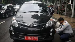 Petugas Dinas Perhubungan DKI Jakarta terlihat sedang mengempiskan mobil yang terparkir di depan Gedung DPRD, Jakarta, Senin (12/1/2015).  (Liputan6.com/Johan Tallo)