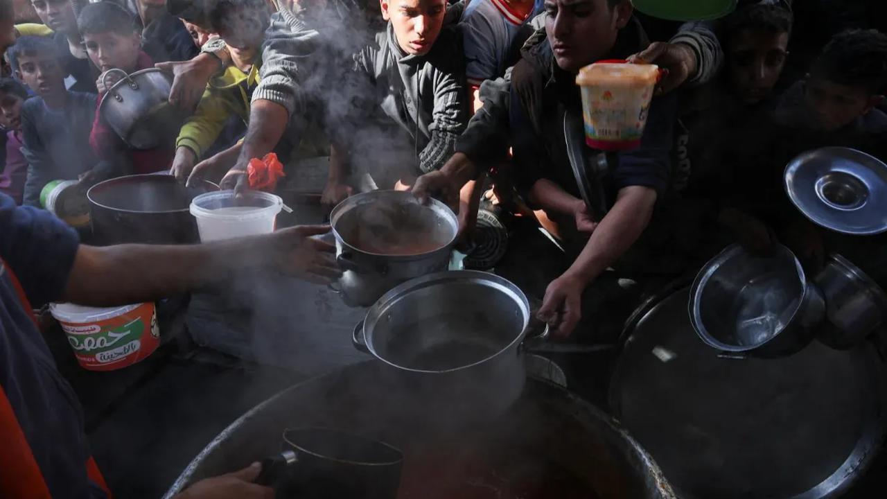 Warga Palestina berebut antrean untuk mendapatkan bagian makanan dari bantuan kemanusiaan di kamp pengungsi di Rafah, di selatan Jalur Gaza (2/12/2023).<br>
