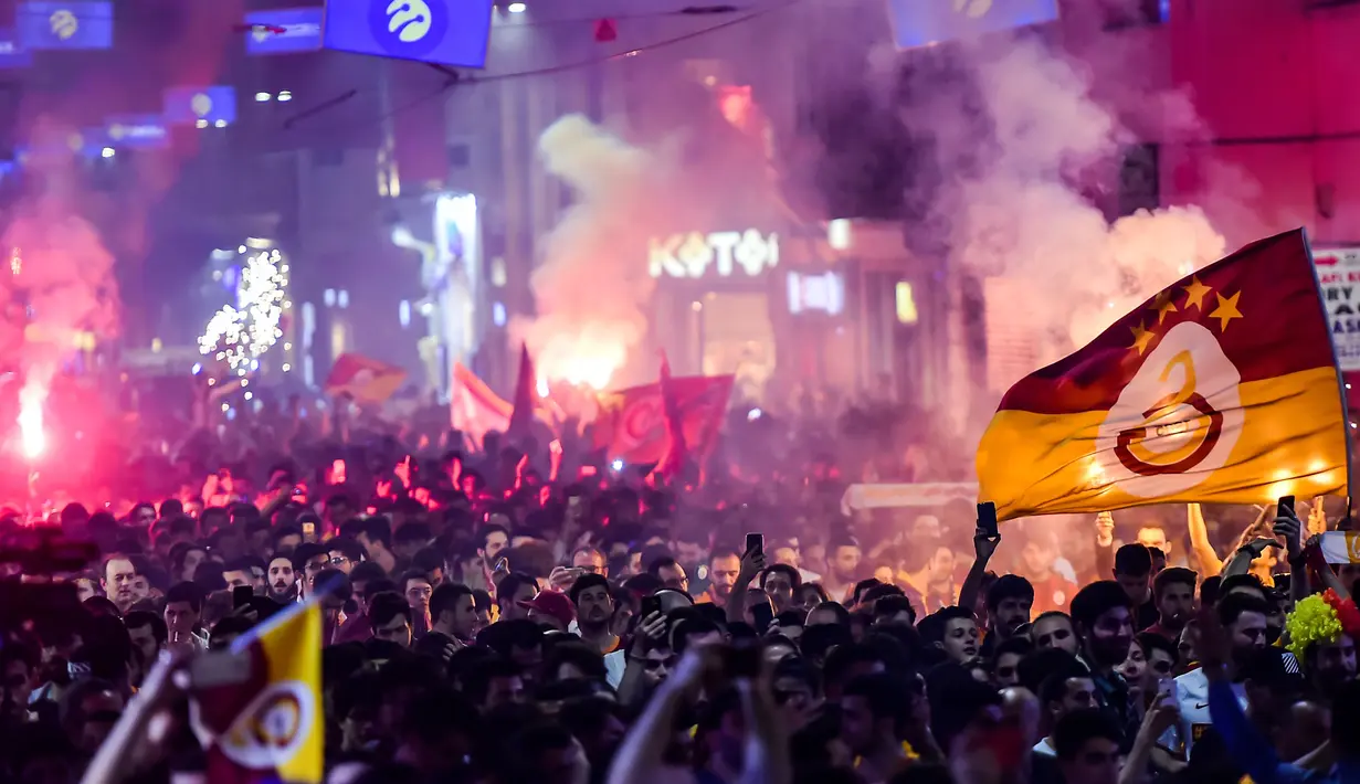 Suporter Galatasaray menyalakan flare saat merayakan kemenangan timnya meraih gelar Liga Turki usai pertandingan melawan Istanbul Basaksehir di Turk Telekom Arena di Istanbul (19/5/2019). Galatasaray memastikan gelar liga Turki ke-22 usai mengalahkan Istanbul Basaksehir 2-1. (AFP Photo/Yasin Akgul)