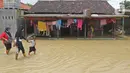 Warga berjalan melintasi rumah yang terendam banjir di Desa Karangligar, Kecamatan Telukjambe Barat, Karawang, Jawa Barat, Kamis (10/2/2021). Banjir akibat meluapnya sungai Citarum dan Cibeet tersebut membuat ratusan rumah terendam banjir dan ratusan hektar sawah. (Liputan6.com/Herman Zakharia)